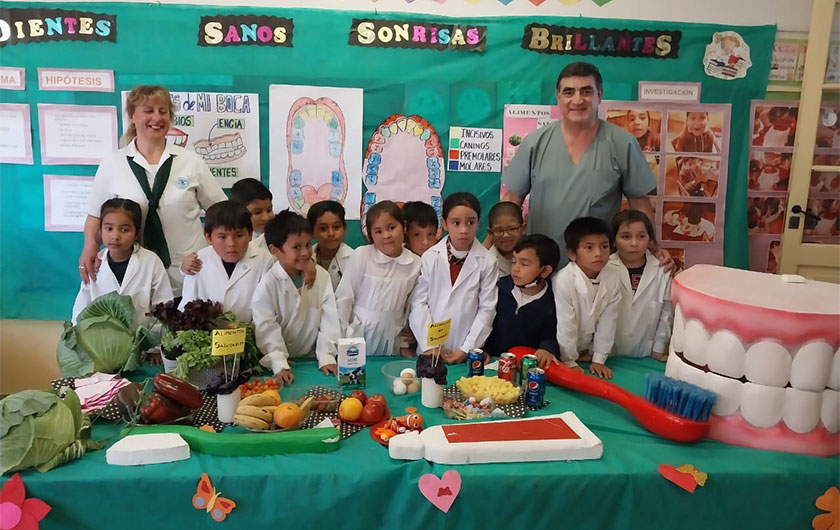 grupo de alumnos y maestra en feria de ciencias junto a un adontologo