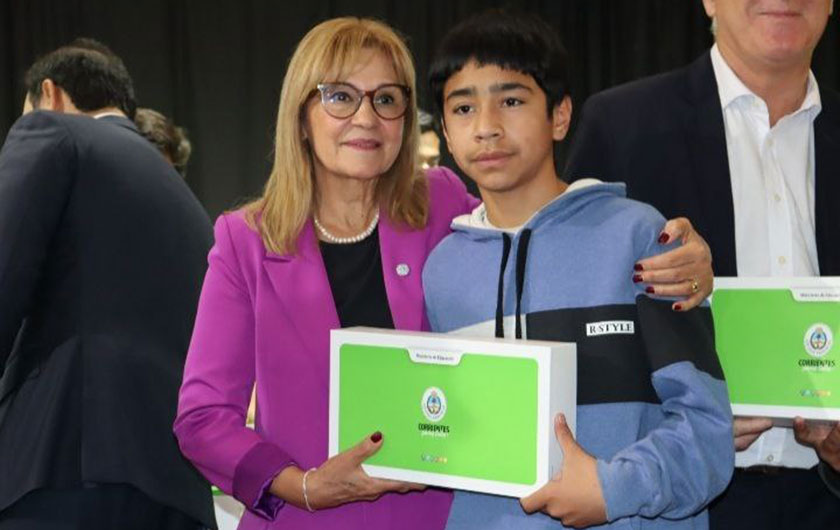 Ministra Práxedes López con alumno entregando notebook