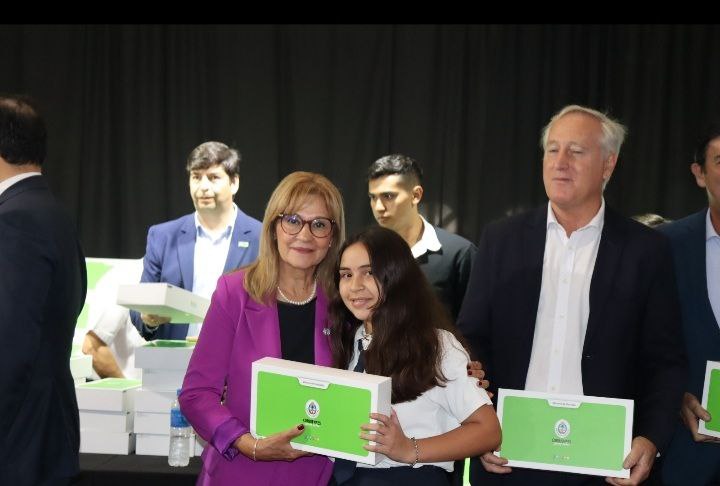 Ministra Práxedes López con alumna entregando notebook